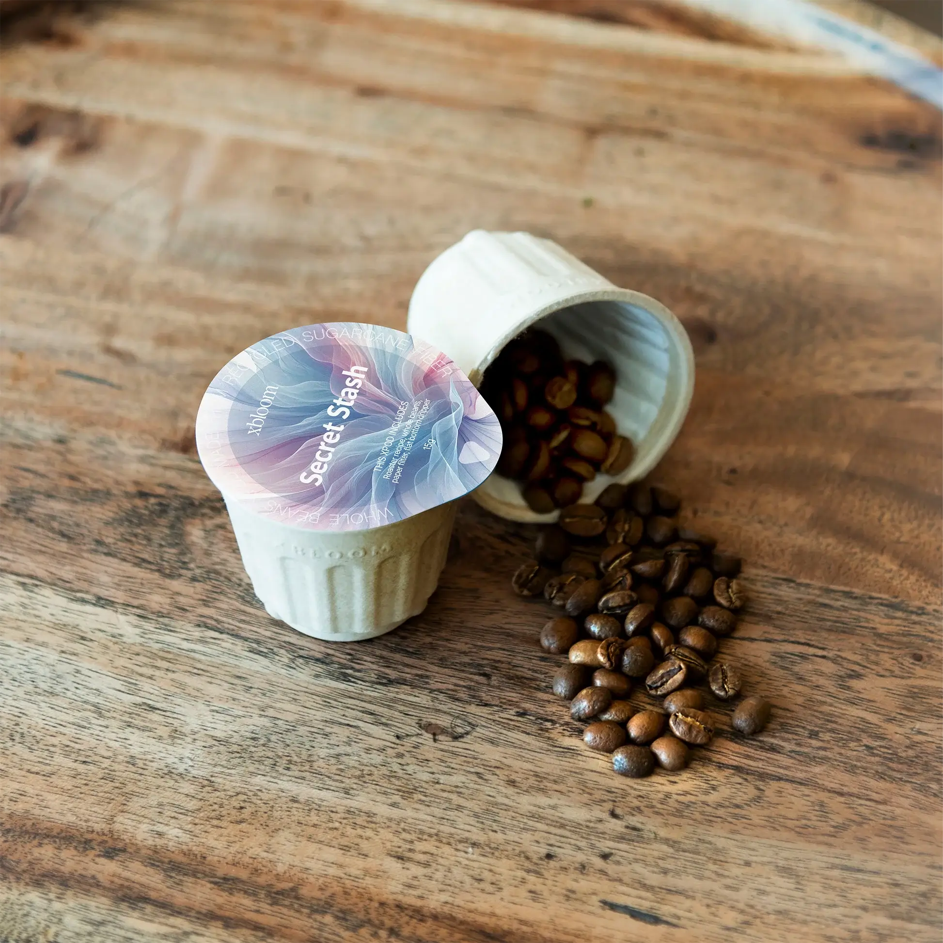 Two xPods with coffee beans on a wooden surface, one open showing 'Secret Stash' branding.