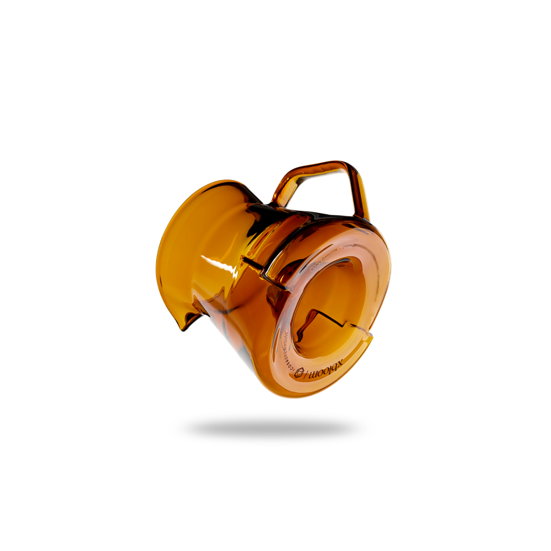 Amber-colored glass object with a handle on a white background