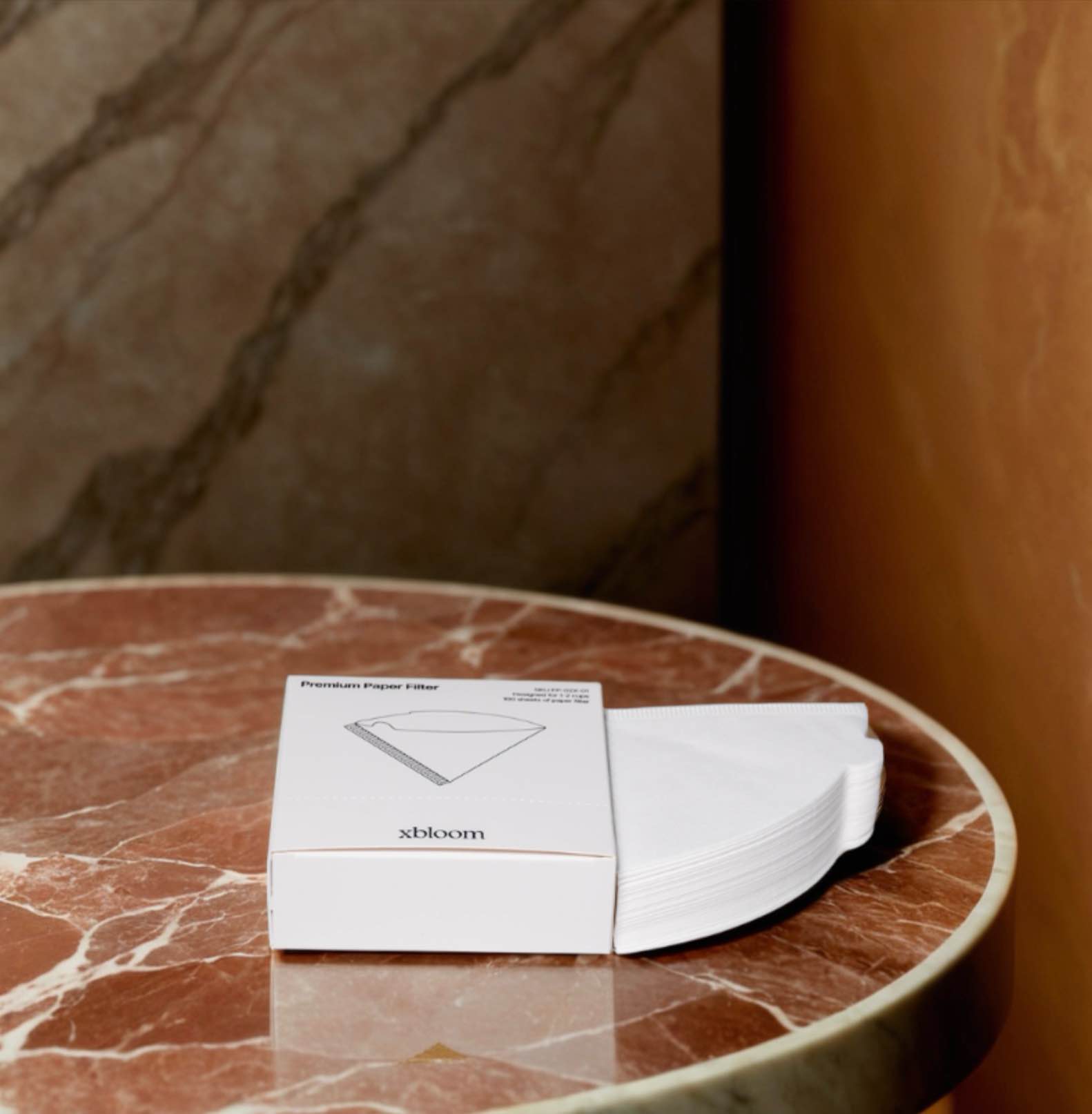 A pack of white conical filter papers placed on a marble surface.