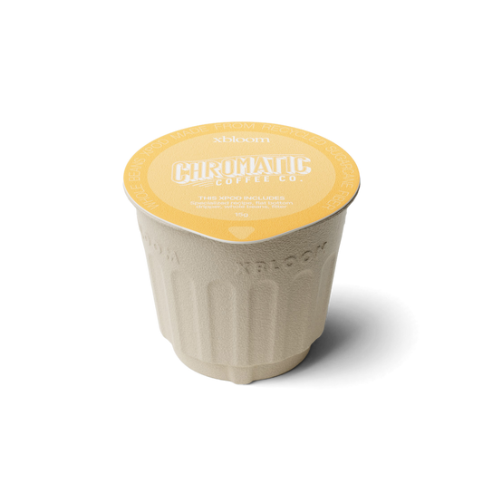 Single-serve coffee cup with yellow lid and branding on a white background