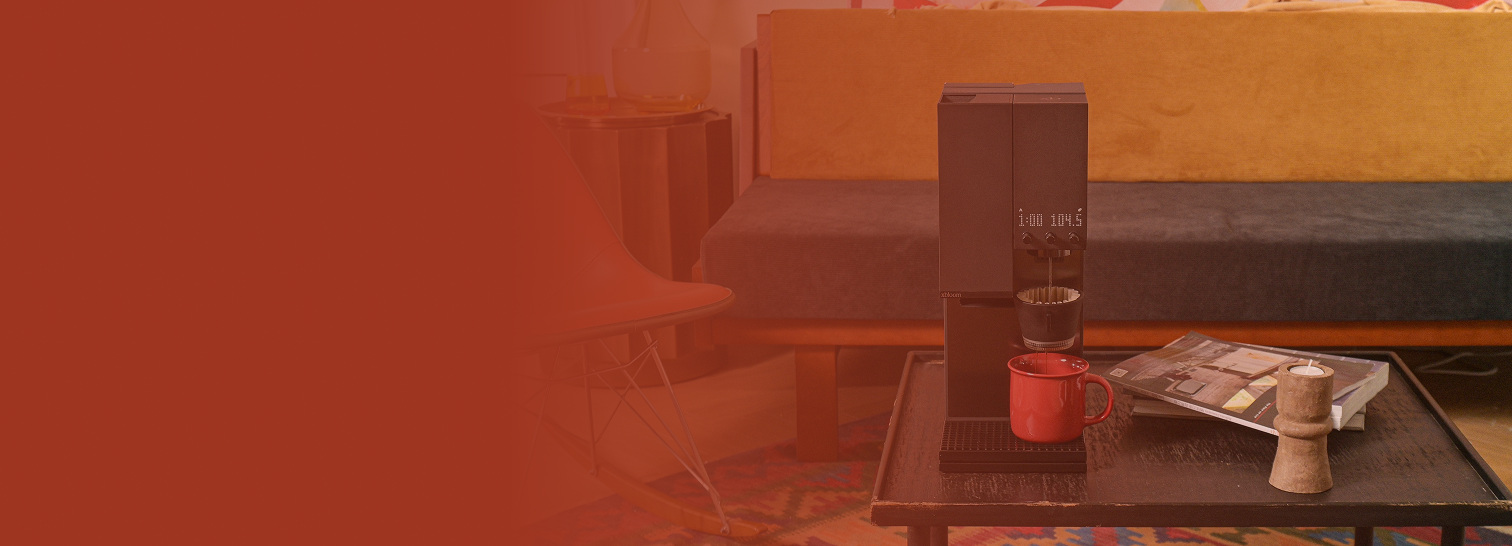 xBloom Studio and red mug on a table with a blurred background.