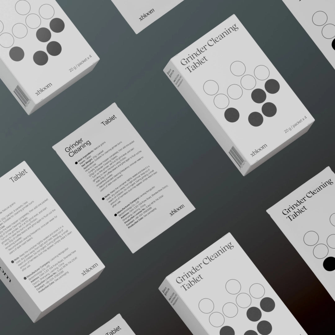 Multiple xBloom Grinder Cleaning Tablet boxes and packets arranged in a repeating pattern on a grey background, showcasing the brand's clean and professional aesthetic.