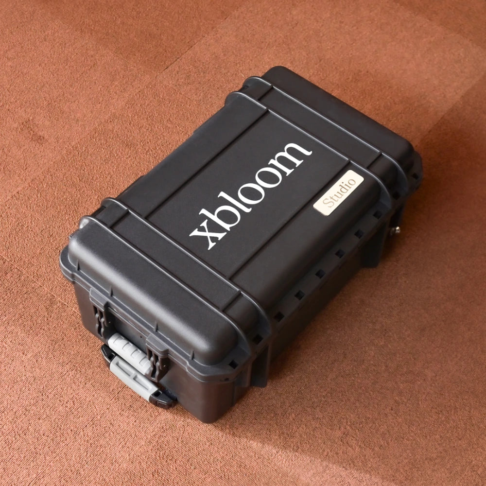 Black hard-shell case with 'xbloom' branding on a brown textured surface