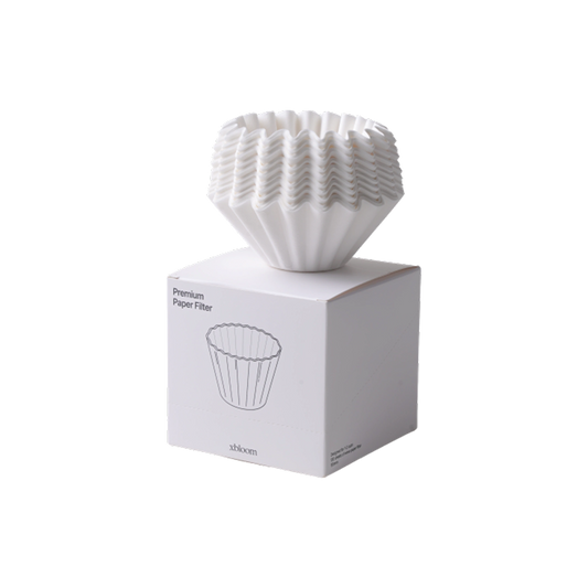A white pleated paper coffee filter resting on top of its white retail box, photographed on a clean white background. The box has a simple line drawing of the filter and the text 'Premium Paper Filter' and '84mm'.